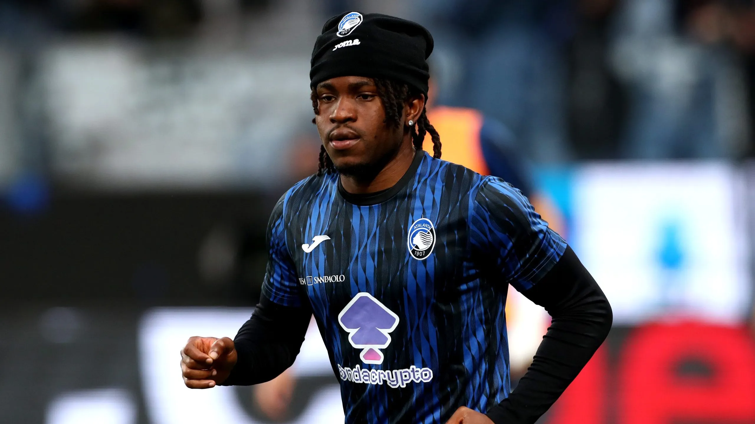 Ademola Lookman, usando camisa azul com listras pretas e gorro preto. Foto: Marco Luzzani/Getty Images